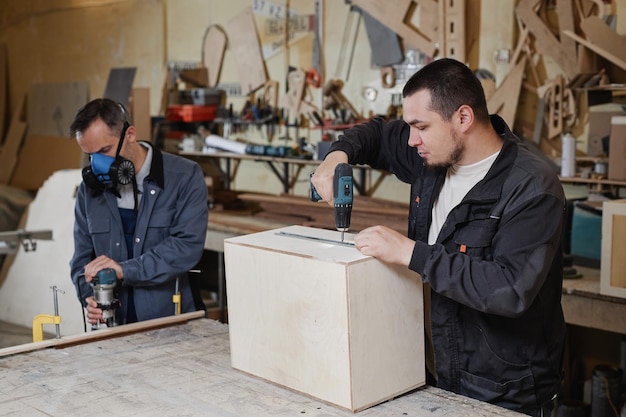 Retrato de dois trabalhadores do sexo masculino construindo móveis de madeira no espaço de cópia da oficina da fábrica