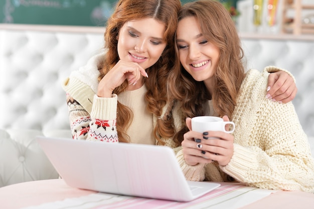 Retrato de duas belas moças usando laptop