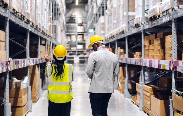 Retrato de duas equipes de engenheiros afro-americanos, detalhes do pedido de remessa no tablet, verifique mercadorias e suprimentos nas prateleiras com estoque de mercadorias na indústria de logística de armazém de fábrica e exportação de negócios