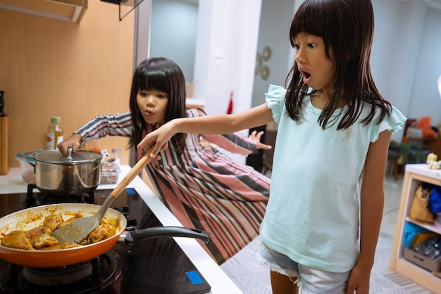 Retrato de duas garotinhas asiáticas cozinhando na cozinha