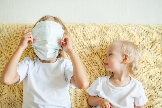 Retrato de duas irmãs usando máscaras médicas de proteção, a irmã mais velha ajuda a mais nova