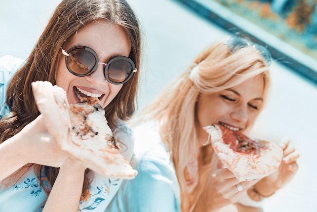 Retrato de duas jovens comendo pizza