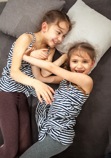Retrato de duas jovens irmãs se empurrando na cama