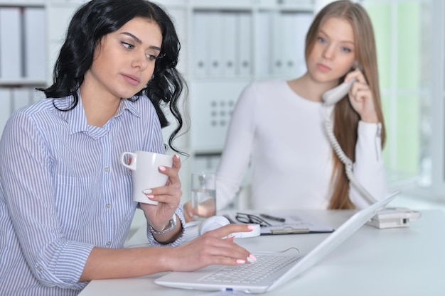 Retrato de duas jovens trabalhando no escritório com laptop