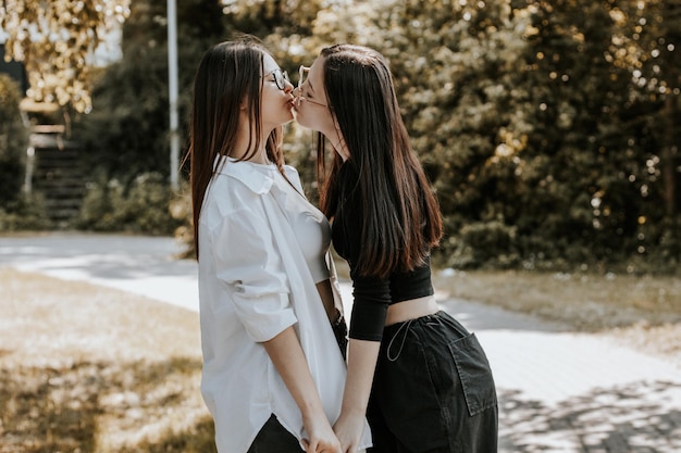 Retrato de duas lindas garotas caucasianas se beijando no parque