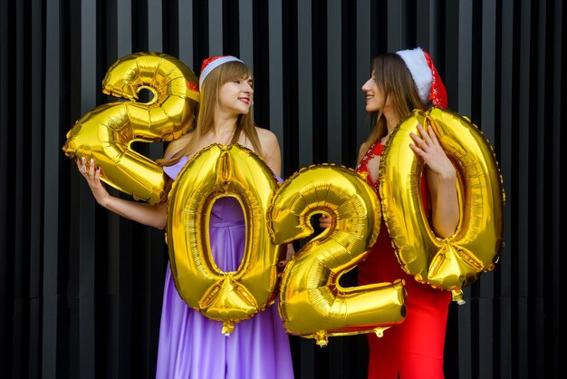 Retrato de duas lindas garotas na véspera de ano novo usando elegantes vestidos de noite