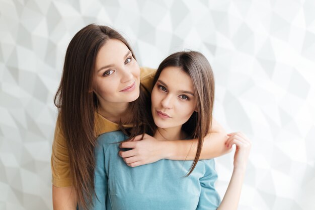 Foto retrato de duas lindas irmãs gêmeas em pé e se abraçando