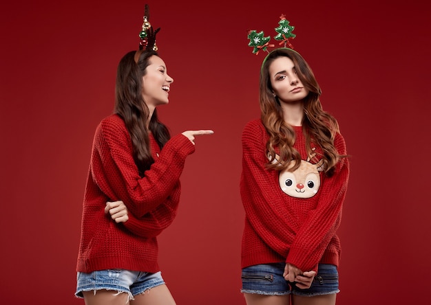 Retrato de duas melhores amigas malucas em um suéter aconchegante de inverno com atributos de Natal posando