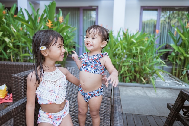 Retrato de duas meninas asiáticas em trajes de banho sorrindo, olhando para a câmera