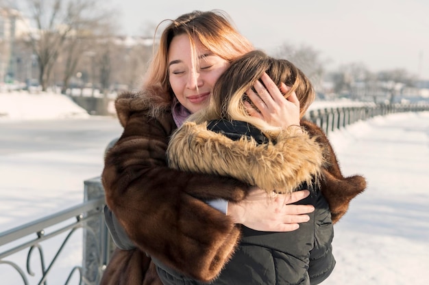 retrato de duas mulheres abraçando no inverno na margem do rio congelado