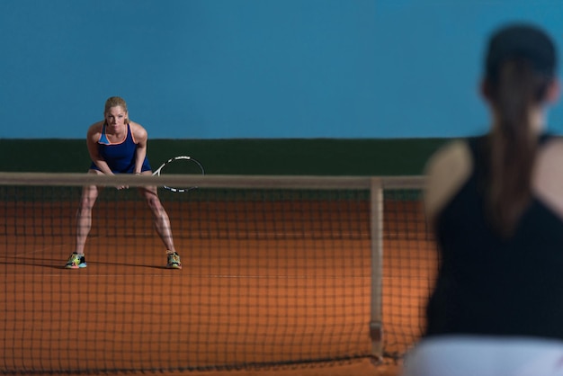 Retrato de duas mulheres bonitas jogando tênis indoor isolado em preto