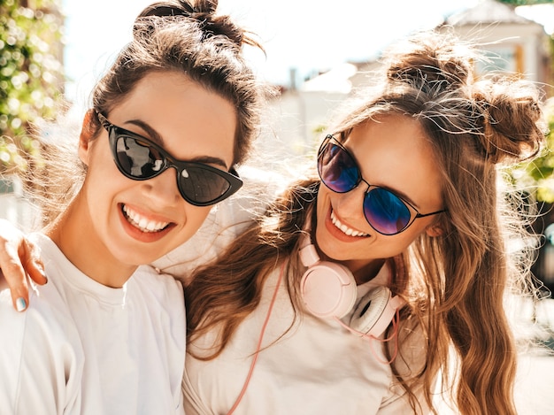 Retrato de duas mulheres jovens e bonitas sorridentes hippie em roupas da moda de verão camiseta branca