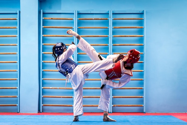 Retrato de duas mulheres jovens em quimono e atletas de taekwondo de sutura lutando no ginásio Esportistas demonstrando o conceito de treinamento duro de arte marcial taekwondo