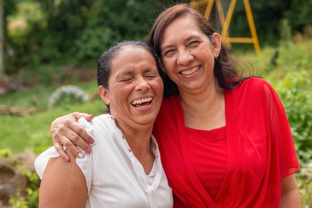 Foto retrato de duas mulheres latinas mais velhas abraçando e rindo juntas a melhor amizade