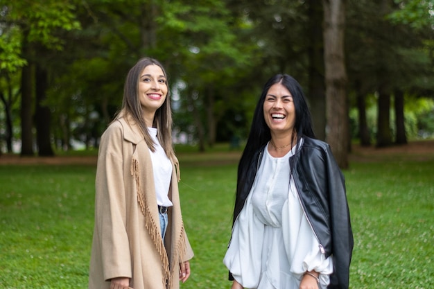 Retrato de duas mulheres sorridentes olhando para a câmera no parque