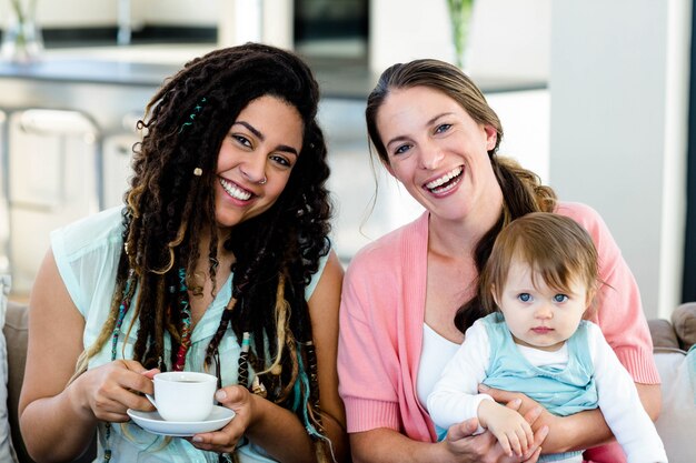 Retrato, de, duas mulheres, sorrindo, e, sentando sofá, com, um, bebê