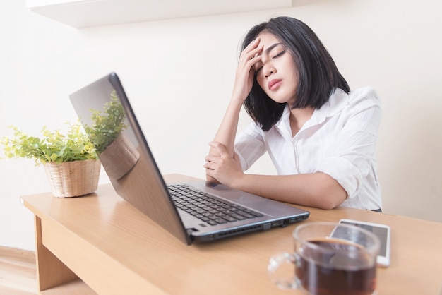 Retrato de empreendedor fêmea deprimido que senta-se na frente do computador ao trabalhar no escritório.