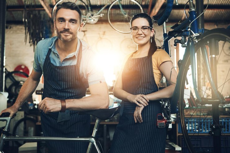 Foto retrato de empregado e loja de reparo de bicicletas com sorriso de mecânico técnico e trabalho de manutenção serviço de oficina e dono de negócio feliz com pessoal e bicicleta para consertar com avental e orgulho