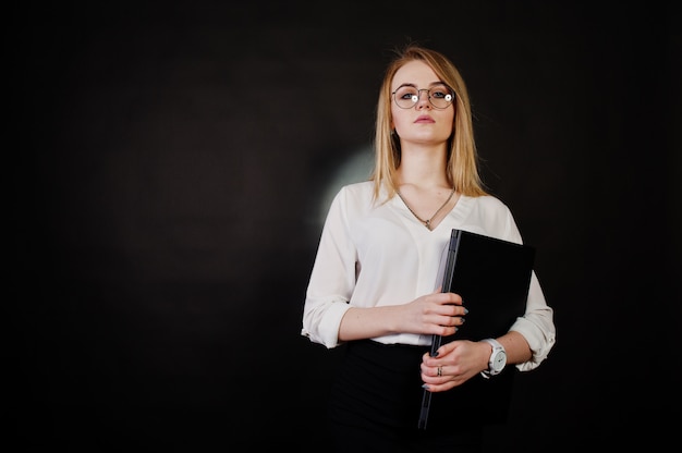 retrato de empresária loira de óculos, blusa branca e saia preta segurando laptop contra. Mulher de sucesso e conceito de menina elegante.