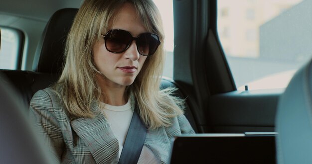 Retrato de empresária trabalhando em laptop em carro de negócios Linda senhora sentada no banco de trás do automóvel