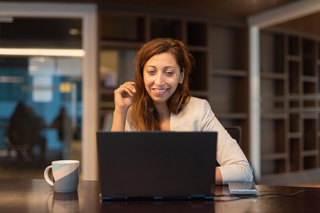 Retrato de empresária usando laptop à noite no escritório