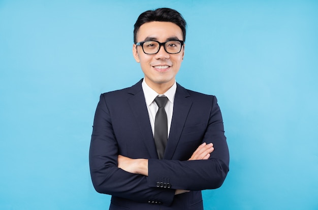 Retrato de empresário asiático com os braços cruzados e sorrindo em uma parede azul