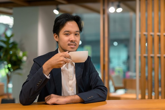Retrato de empresário asiático em uma cafeteria tomando café
