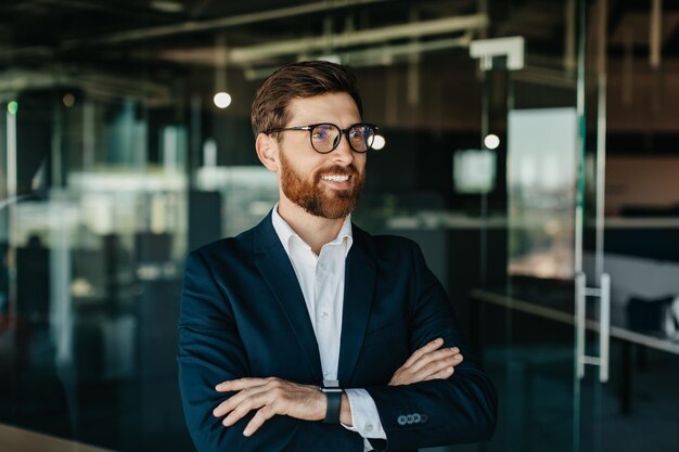 Retrato de empresário bem sucedido em terno posando com as mãos cruzadas olhando para longe e sorrindo espaço de cópia