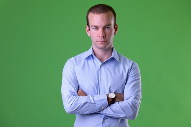 Retrato de empresário com os braços cruzados contra o fundo verde