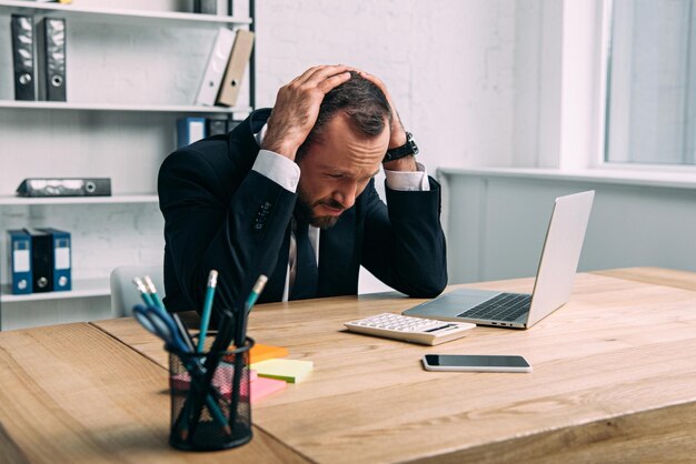 Retrato de empresário estressado no local de trabalho com laptop no escritório