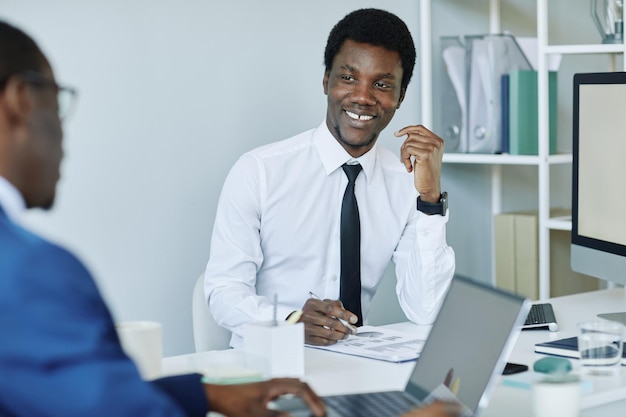 Retrato de empresário negro sorridente em reunião no escritório mínimo