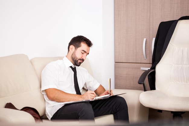 Foto retrato de empresário trabalhando no escritório no sofá colocando longas horas de trabalho. empresário em ambiente profissional