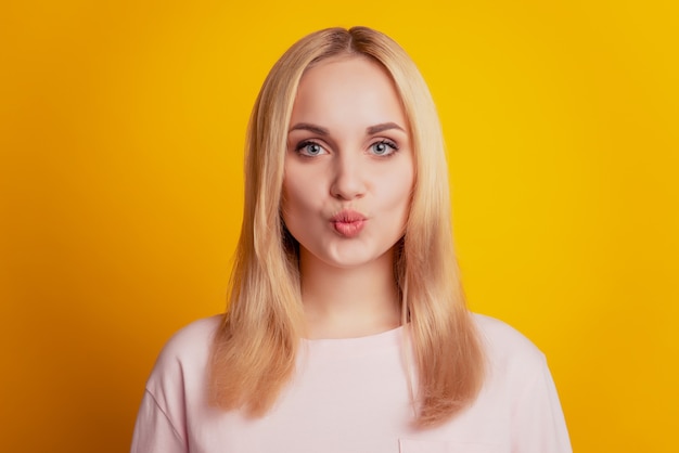 Retrato de encantadora e adorável senhora glamour mandando beijo no ar sobre fundo amarelo