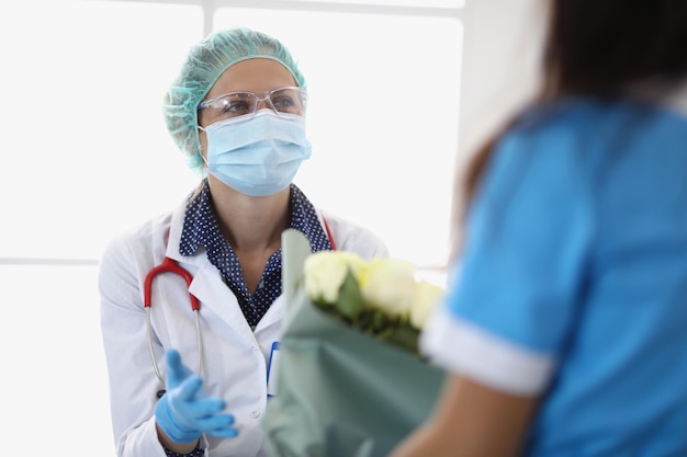 Retrato de enfermeira recebendo flores como mulher qualificada de gratidão em uniforme médico com