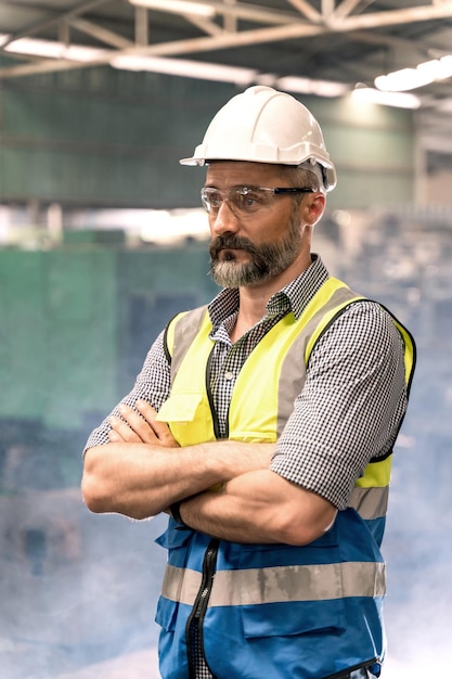 Retrato de engenharia usando capacete e segurança unifrom em pé na fábrica. Industrial e operário.