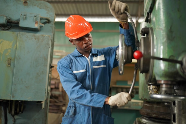 Retrato de engenheiro de indústria pesada profissional/trabalhador vestindo uniforme de segurança, óculos de proteção e capacete. Em segundo plano Grande Fábrica Industrial Desfocada