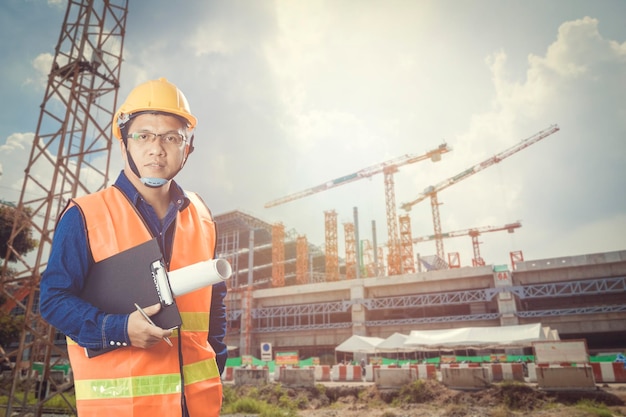 Retrato de engenheiro de pé no local de construção contra o céu