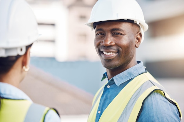 Retrato de engenheiro ou arquiteto de homem negro com equipamento de segurança de capacete e reflexo de lente ao ar livre Confiar em especialista e sorriso feliz de um trabalhador da construção civil ou gerente com trabalhador no local para desenvolvimento de projetos