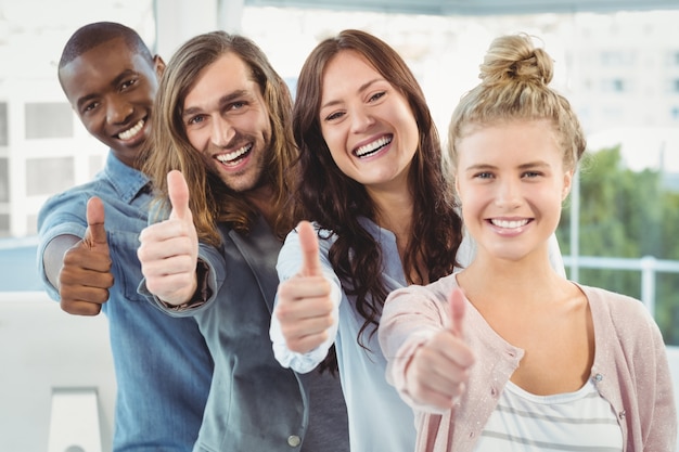 Retrato de equipe de negócios feliz com polegares para cima enquanto está em pé