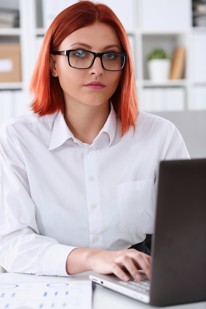 Retrato de escritório de mulher ruiva de negócios sentar mesa