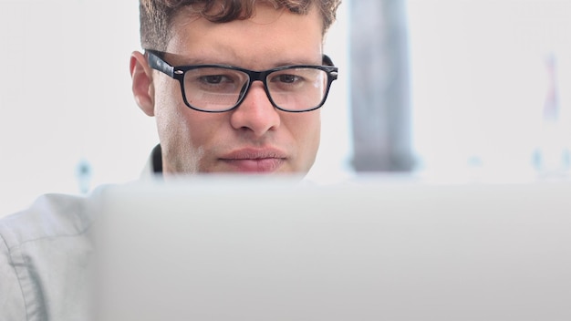 Retrato de escritório moderno de um elegante empresário hispânico trabalhando em um laptop