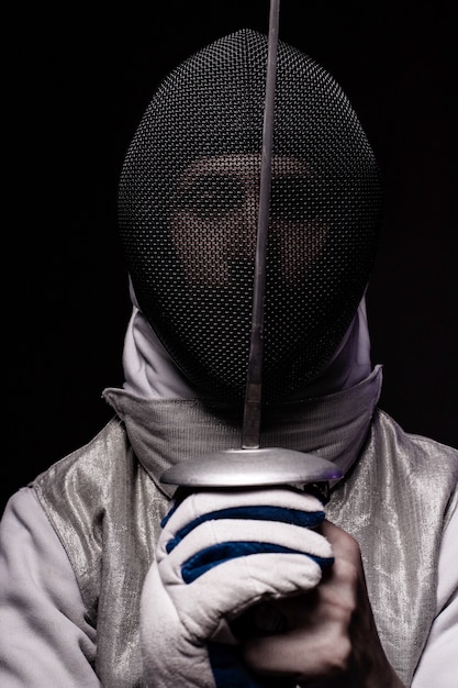 Foto retrato de esgrimista masculino em máscara e folha, realizando luta