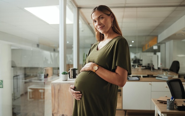 Retrato de estômago e de uma mulher grávida no escritório de sua empresa no início de sua licença de maternidade da empresa e gravidez com uma jovem empregada confiante ou mãe no local de trabalho