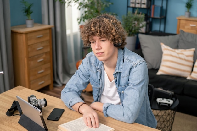 Retrato de estudante adolescente aprendendo com curso online sentado na mesa em sua sala de estar em casa