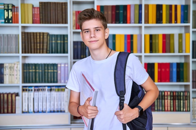 Retrato de estudante adolescente masculino olhando para a câmera na biblioteca