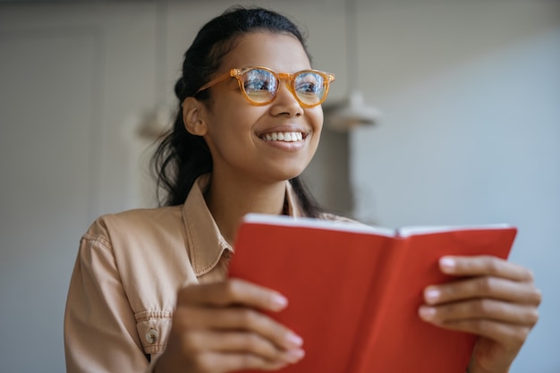 Foto retrato de estudante feliz em óculos elegantes, estudando, aprendendo línguas, lendo um livro, preparação para o exame, conceito de educação
