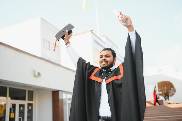 Retrato de estudante indiano bem sucedido em vestido de formatura polegar para cima