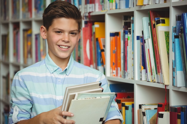 Retrato de estudante segurando livros na biblioteca