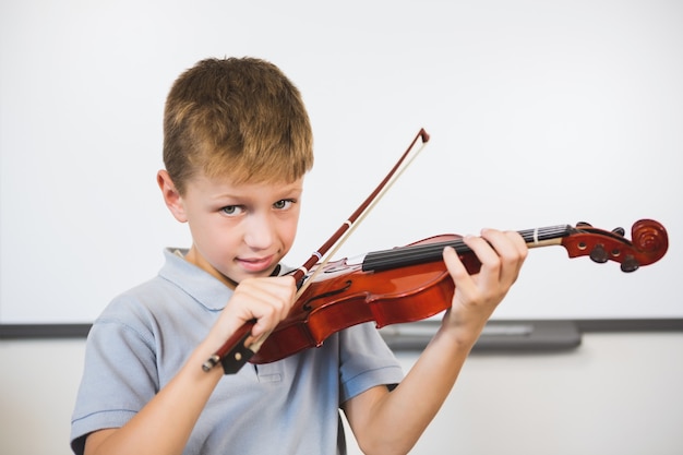 Retrato de estudante sorridente tocando violino na sala de aula