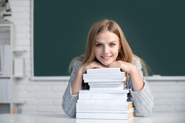 Retrato de estudante universitária estuda lição na escola ou universidade Feche o retrato de uma jovem atraente feliz estudante com livros no quadro-negro em sala de aula